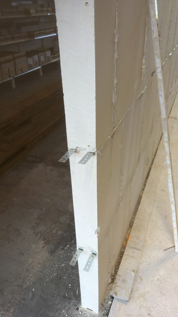 Detail van de verankering van een 10 cm gipsblokken tussenwand aan de staalconstructie in een loods in Utrecht.